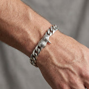 Men's 10mm sterling silver curb chain bracelet with decorative circular clasp detail worn on a masculine wrist, showcasing the chunky linked design and polished silver finish