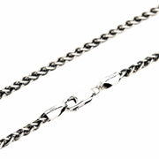 A close-up of a solid sterling silver wheat chain necklace, showing the intricate braided links and the secure lobster clasp.