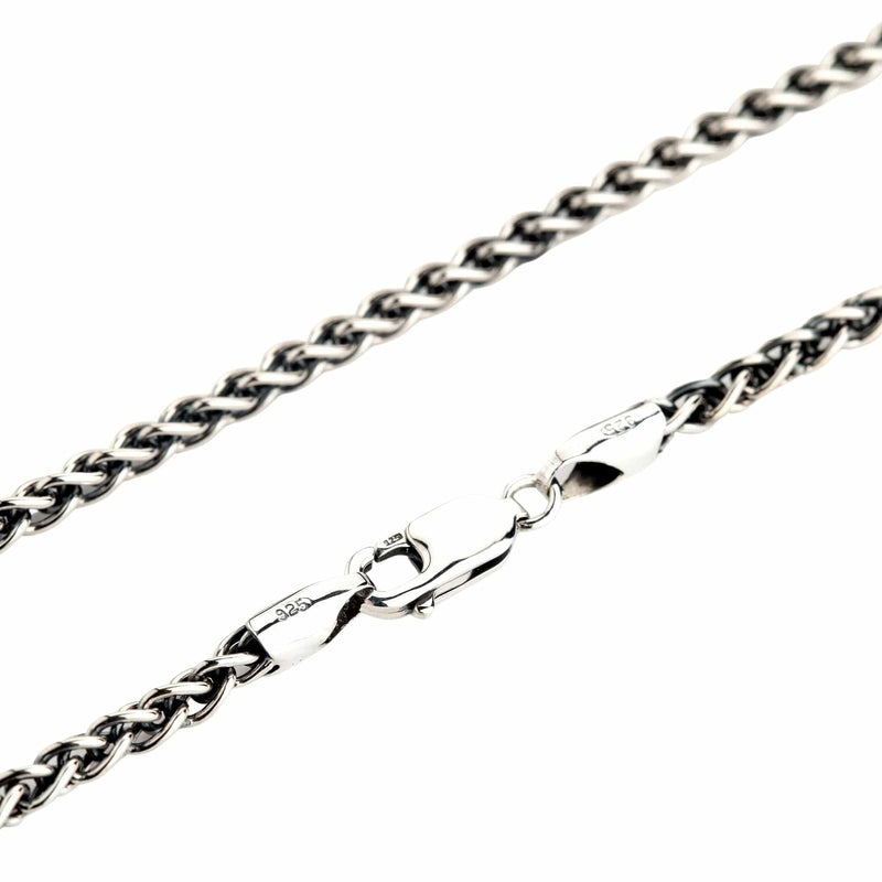 A close-up of a solid sterling silver wheat chain necklace, showing the intricate braided links and the secure lobster clasp.