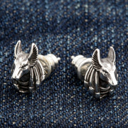 A pair of solid sterling silver Anubis earrings, showing the detailed jackal-headed Egyptian god on a denim background.