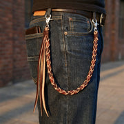 Sidovy av en modell som bär en flätad svart och brun läderplånbokskedja med långa hängande fransar fästa vid bältesöglorna på blå jeans, med silverfärgade spännen och en plånbok i bakfickan.