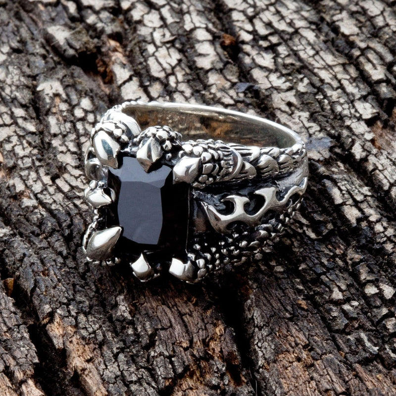 Vue de dessus de la bague à griffes gothique noire, montrant des griffes de dragon saisissant une pierre noire carrée.
