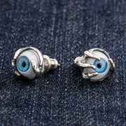 A pair of blue eyeball stud earrings in sterling silver, clutched by a gothic claw design.