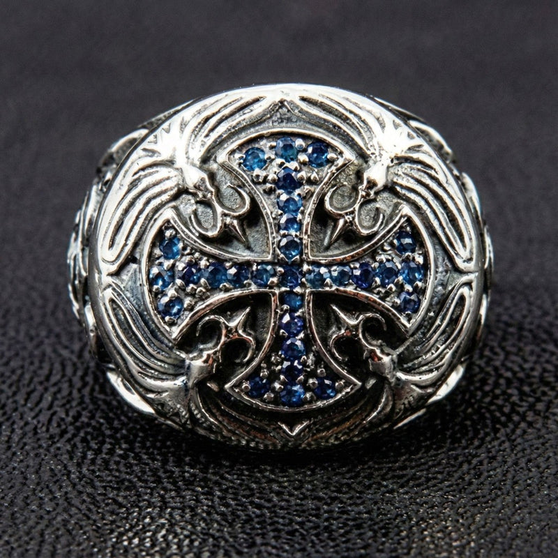 Vista dall'alto dell'anello con croce dei Cavalieri Templari, impreziosito da pietre CZ zaffiro blu incastonate a pavé e dettagli floreali incisi in argento.