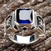 A solid sterling silver knight ring with a large, rectangular blue stone and intricately carved shield details on the side.