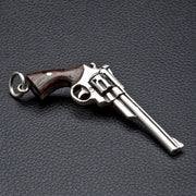 A solid sterling silver cowboy revolver pendant featuring an authentic, dark wood grip and detailed craftsmanship.