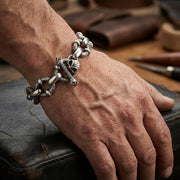 A close-up of a biker hand wearing the Crazy Skull 925 sterling silver biker bracelet featuring a 17mm link width in soft studio lighting.
