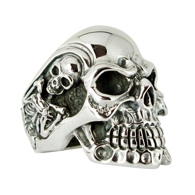 Vista ravvicinata di tre quarti di un anello a forma di teschio in argento sterling .925, caratterizzato da denti dettagliati, rilievi a ossa incrociate e finitura ossidata.