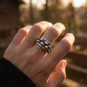 Double skull spinner ring in 925 sterling silver worn on man's finger with warm lighting