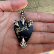 A solid sterling silver dragon claw guitar pick holder pendant, shown securely holding a black guitar pick.