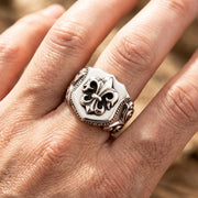 Close-up of a male hand wearing a Fleur de Lis ring with a 15mm face size, captured in soft sunlight editorial photography.