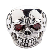 Direct front view of a grinning skull ring with red garnet-colored eyes, emphasizing the aggressive teeth and nose detail.