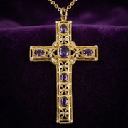 Gold amethyst bishop cross pendant with oval-cut purple gemstones and Byzantine filigree displayed on royal purple velvet