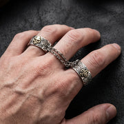 Close-up of a white male hand wearing a goth chained two-finger ring featuring soft studio lighting and a punk-style editorial aesthetic.