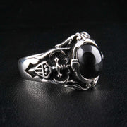 Egy ferde nézet a gótikus fekete ónix pecsétgyűrűről, kiemelve a részletes pajzs címert a gyűrűsávon.