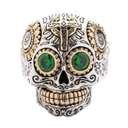 Un anello in argento sterling a forma di teschio zucchero con occhi CZ verde brillante e accenti in ottone dorato.