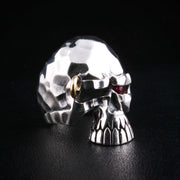 A solid sterling silver hammered punk skull ring with a single, fiery red CZ eye and a unique gold-tone eyebrow piercing.