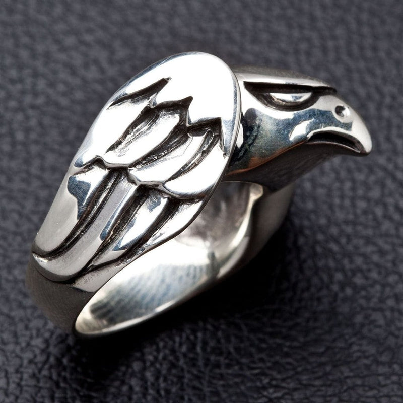 Perfil lateral de anillo artesanal de halcón en plata, destacando las plumas esculpidas y la banda lisa.