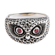A front-on view of the handmade silver owl head ring with red eyes, isolated on a white background.