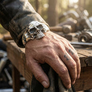 Poignet d'homme portant une lourde manchette en argent sterling massif représentant un crâne de motard, mettant en valeur sa taille massive.