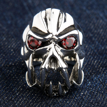 A front view of the heavy sterling silver fang devil ring with red CZ eyes, resting on a denim background.