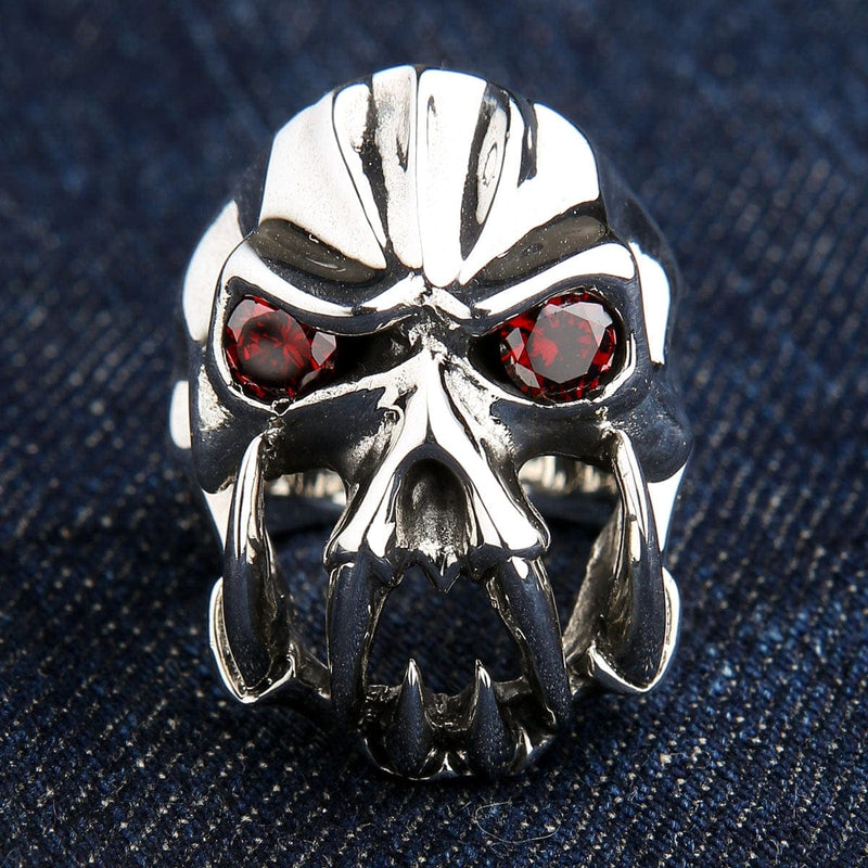 En forsidebillede af den tunge sterling silver fang djævelsring med røde CZ øjne, hvilende på en denim baggrund.