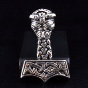 A heavy silver Thor's Hammer (Mjolnir) pendant with intricate Viking knotwork and a carved Norse face.