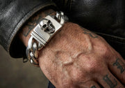 Heavy skull curb chain sterling silver biker bracelet worn on tattooed wrist