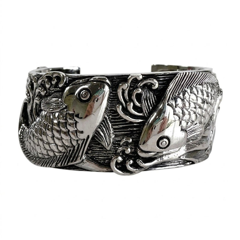Front view of a 38mm-wide solid sterling silver cuff bracelet featuring two carved koi fish swimming through swirling waves.