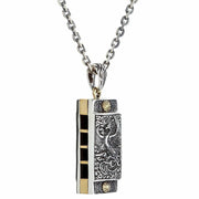 A sterling silver and brass Japanese phoenix harmonica pendant, showing the detailed Hō-ō (phoenix) engraving.