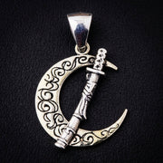 Sterling silver pendant displaying a katana sword passing through a crescent moon with swirling engravings.