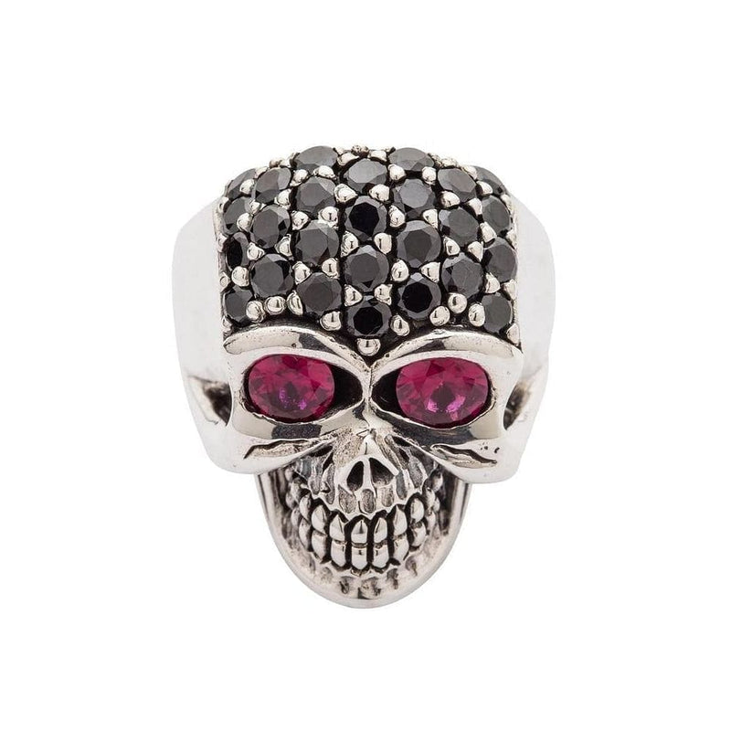 An anillo de plata esterlina con forma de cráneo femenino, cuyo cráneo está completamente pavimentado con cristales negros y dos ojos grandes y profundos de piedra roja.