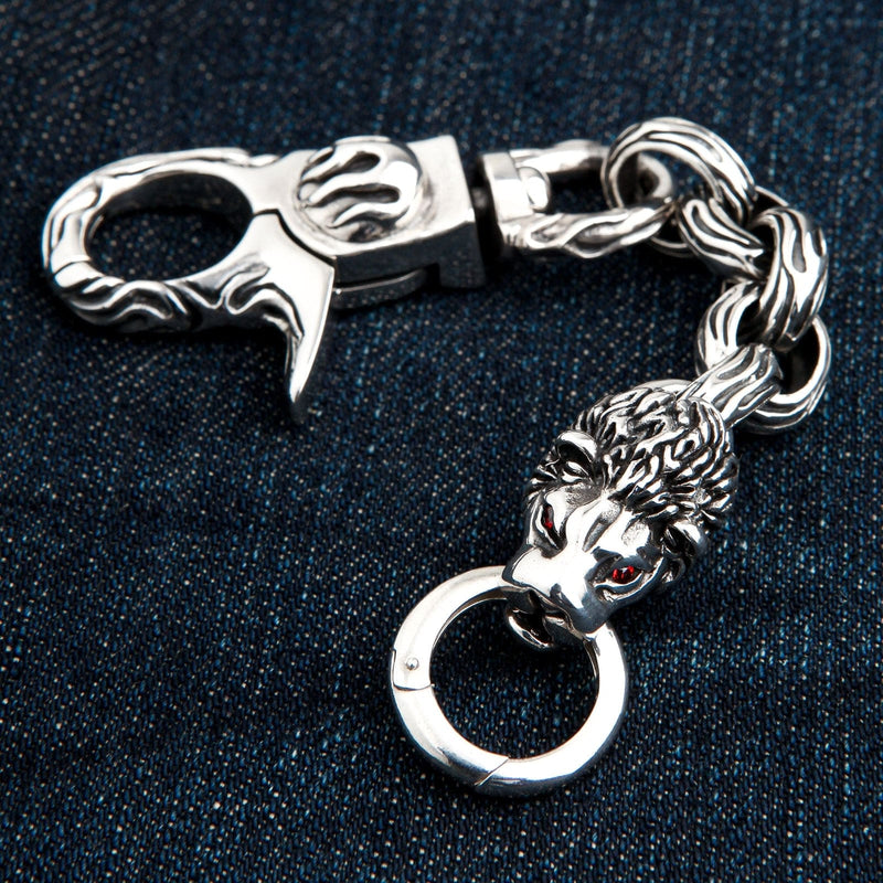 En 77-grammig solid silver lejonhuvud biker nyckelring med röda ögon, på mörk denim.