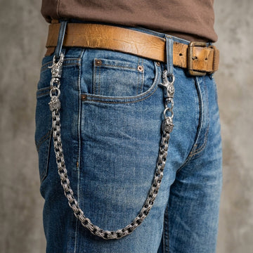 Homem a usar uma corrente de carteira com cabeça de leão pesada ao lado de uns jeans azuis.