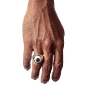 A man's hand wearing the large gothic blue eyeball ring.