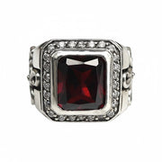 A men's solid sterling silver gothic cross ring, featuring a large red garnet CZ stone and a halo of clear accents.