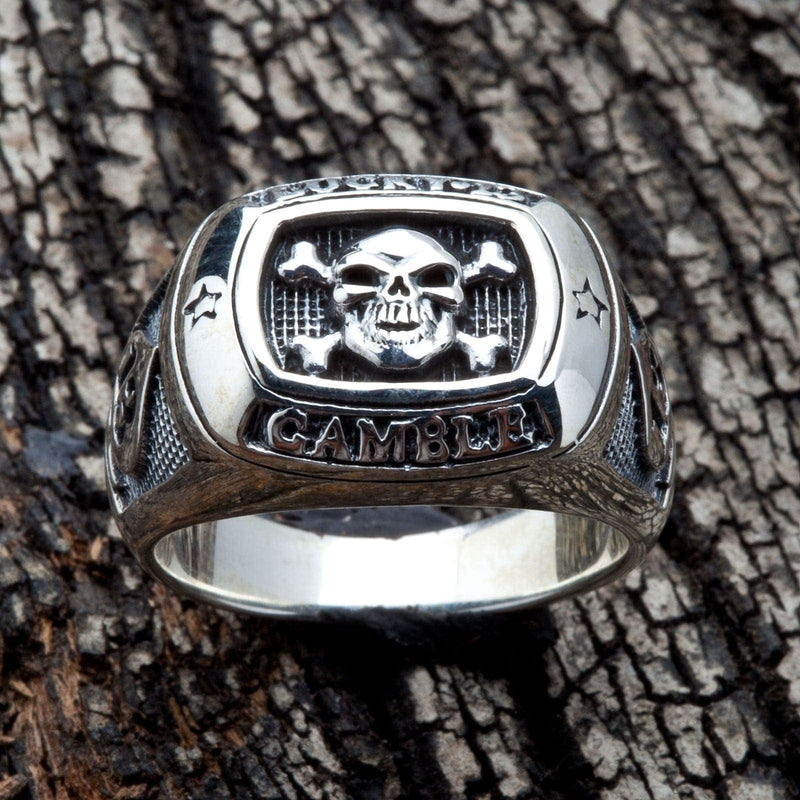 Un anello solido in argento sterling per uomo con una teschio e ossa e la parola 'GAMBLE'.
