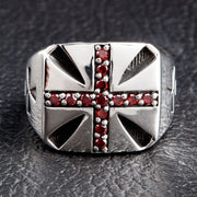 Front view of the men's sterling silver garnet cross ring on a black surface.