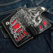 The men's gothic skull wallet with red inlay laid open on a pair of jeans, showing the full design.