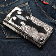 A men's long gothic biker wallet with a black stingray cross on gray lizard skin, shown resting on blue jeans.