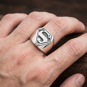 Close-up of a white male hand wearing a large statement ring with a 19mm x 18mm face size, displayed in soft studio lighting.