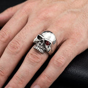 मॉडल ने अपनी उंगली पर लाल ग्रेनेट पत्थर की आंखों के साथ 925 स्टर्लिंग चांदी की खोपड़ी की अंगूठी पहनी हुई है, जो भारी गोथिक बाइकर्स गहनों की शैली को प्रदर्शित कर रही है।