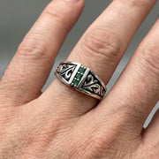Mens Tribal Emerald Sterling Silver Ring worn on finger, featuring intricate tribal swirl carvings and a vertical row of green emerald stones