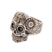 Angled view of sterling silver Calavera ring featuring brass floral eye details