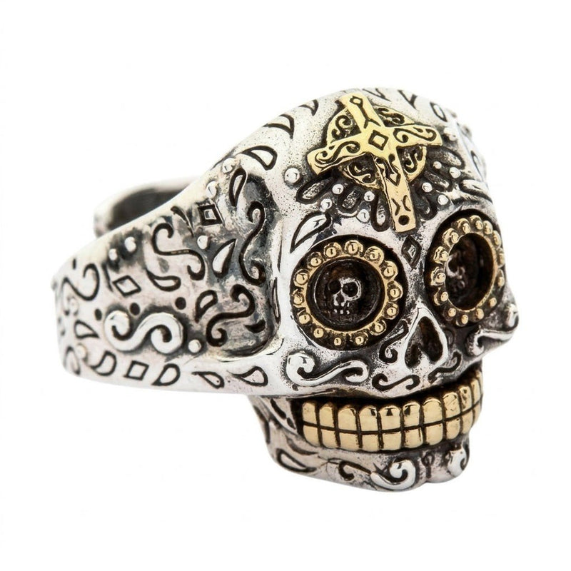 Sterling silver Mexican skull ring angled to show the brass forehead cross, intricate engravings, and brass teeth.