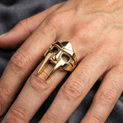 MF Doom gold plated brass mask ring worn on a man's hand showing the gladiator face detail