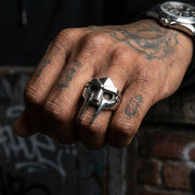 MF DOOM mask sterling silver ring worn on a tattooed fist with graffiti background