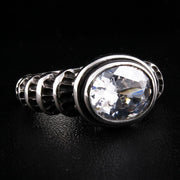 Vinklad vy av en gotisk ring i sterlingsilver med en stor 14x12mm oval klar topas och snidat band med våg- och rankmönster.