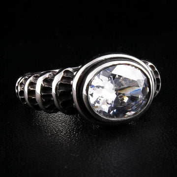 Angled view of a gothic sterling silver ring featuring a large 14x12mm oval clear topaz and carved wave scrollwork band.