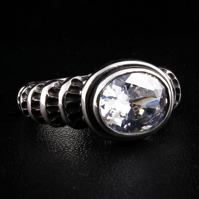 Angled view of a gothic sterling silver ring featuring a large 14x12mm oval clear topaz and carved wave scrollwork band.